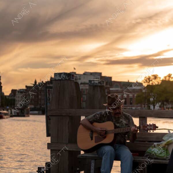 olanda holland paessi bassi the netherlands amsterdam tramonto sunset sundown crepuscolo dusk twilight alba sunrise canale canal channel street musician artist artista di strada musicista chitarra guitar cappello hat